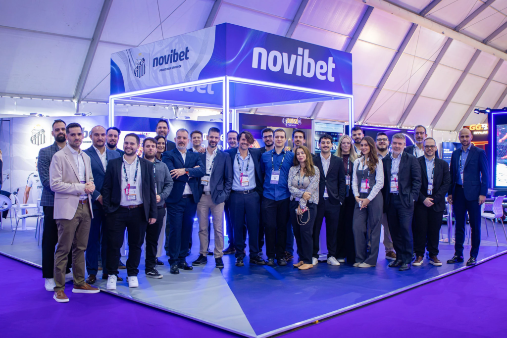 A group of five smiling team members posing for a photo in their booth at the SBC Lisbon Summit at the Feira Internacional de Lisboa (FIL)